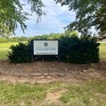 Centerstone Fellowship House sign amid shrubs and trees on a grassy campus.