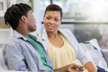 Adult and teenager having a conversation while seated on a couch