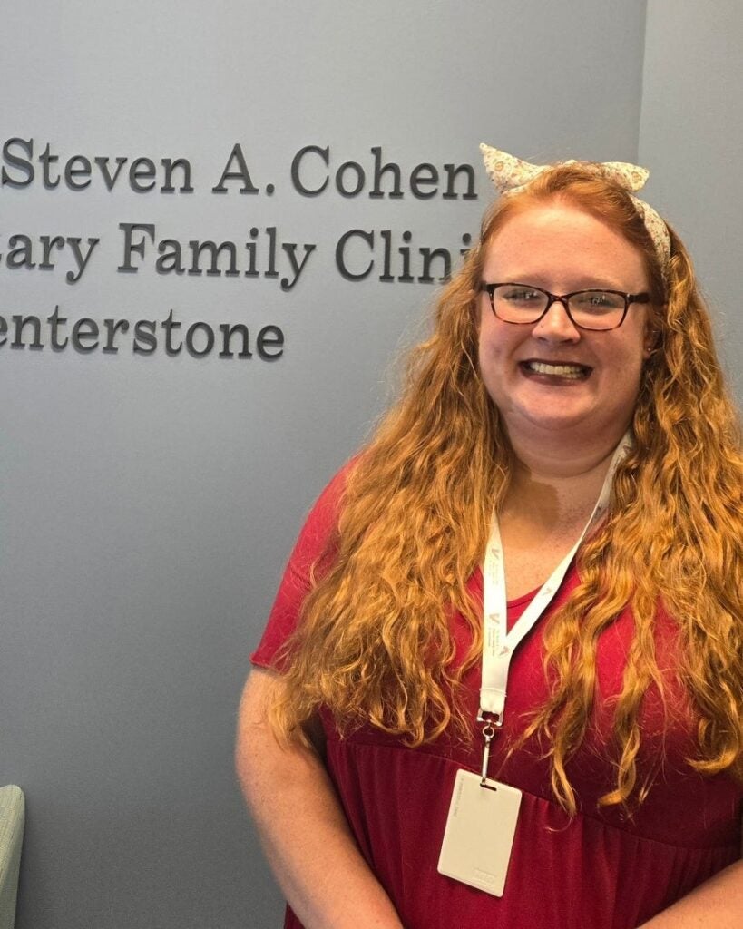 Alexa Smith-Surrett wearing glasses and a lanyard in front of a Centerstone clinic sign