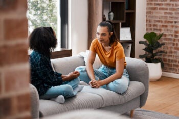 Shot of a young mother and daughter talking while sitting on the couch at home