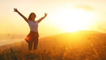 Happy woman   on sunset in nature iwith open hands
