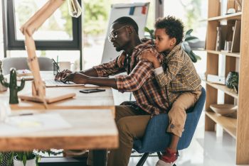 father and son using laptop in office