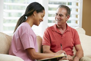 Nurse Discussing Records With Senior Male Patient During Home Visit