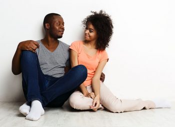 African-american couple looking up, sitting on floor