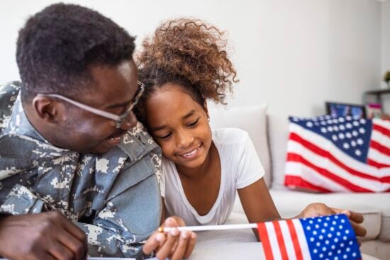 Portrait of happy american family father in military uniform and cute little girl daughter with flag of United States