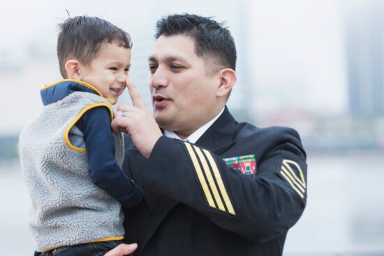 Hispanic military man holding 2 year old son