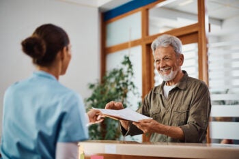 Happy senior man taking his medical paperwork from a nurse at the clinic.