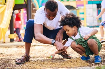 Happy African American Parents play in the playground area toget