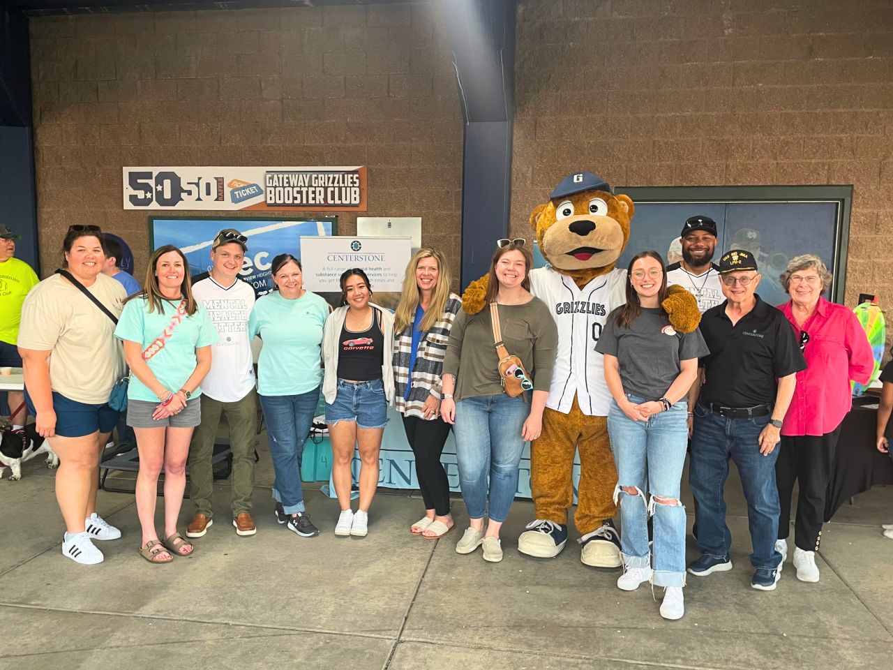 Centerstone staff posing with the Grizzlies mascott at a baseball game.