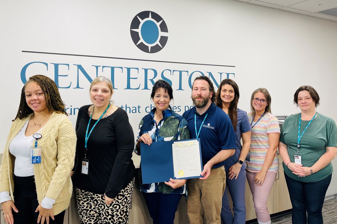 Several Centerstone staff posing for a picture inside a clinic presenting a proclamation.