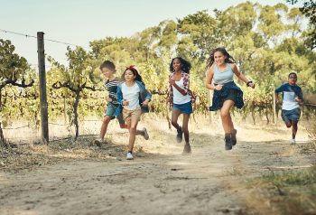 Shot of a group of teenagers running through nature at summer camp.