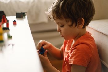 Cute boy is playing constructor at home. Kid playing block toys