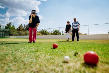 Latino senior woman playing boules with friends.