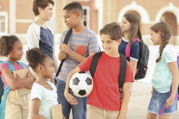 Group of school children, friends talking together on campus.