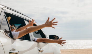 Happy family sitting in the car waving hands travel outside car windows