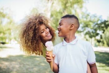 Cute boy eating ice cream and having fun with mom