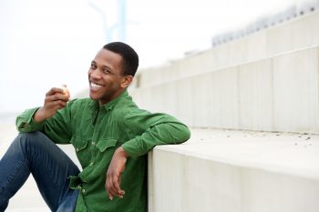 Healthy young man smiling and eating apple
