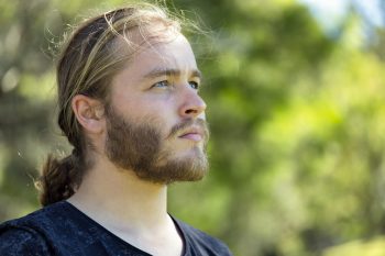Portrait of young man with ponytail, background with copy space