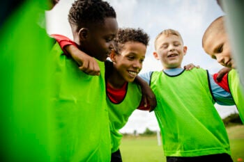 Junior football team huddling together