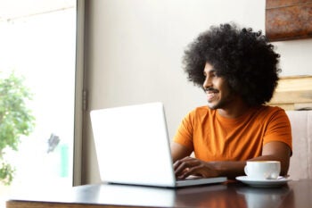 Happy student sitting at table with laptop